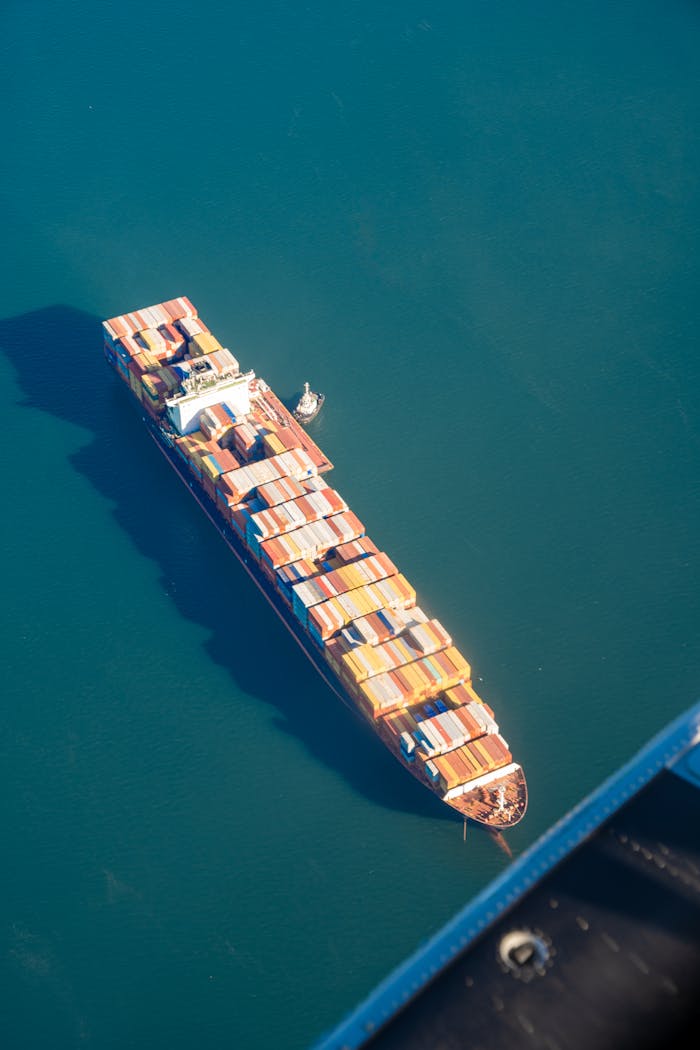 Aerial shot of a container ship in Vancouver, showcasing vibrant cargo against the blue ocean.