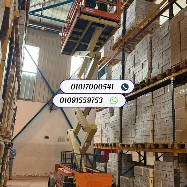 سيزر لفت كهربائي عالي الارتفاع يعمل داخل مخزن أرفف ضخم، مخصص لأعمال الجرد والصيانة المرتفعة في المساحات الضيقة.